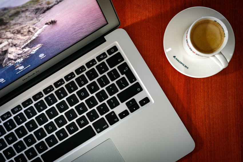 Biurko podczas pracy, laptop oraz filiżanka kawy z logo Małopolska